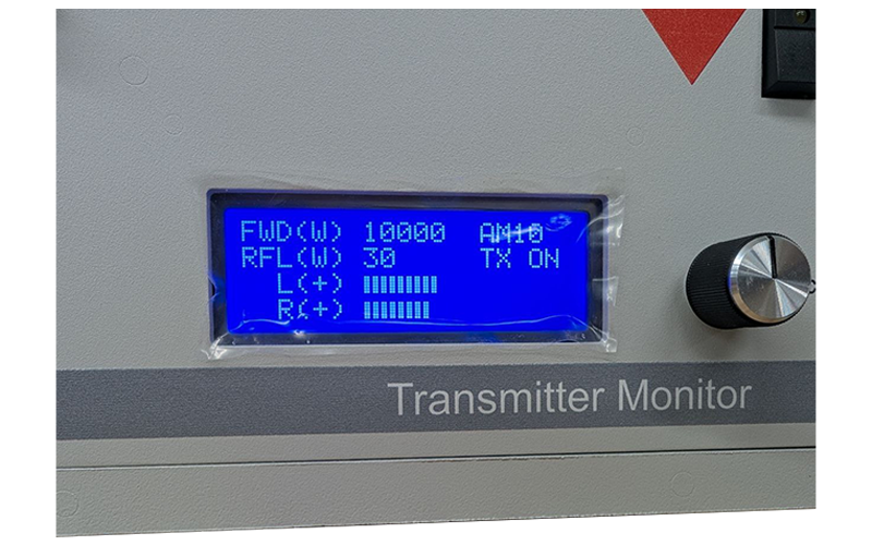 Close-up LCD status display on Broadcast Electronics AM-10A AM transmitter monitor panel showing forward and reflected power readings.