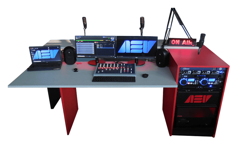 AEV SMART compact radio studio package with red on‑air desk, broadcast console, dual monitors, microphones, laptop, rack equipment and illuminated On Air sign.